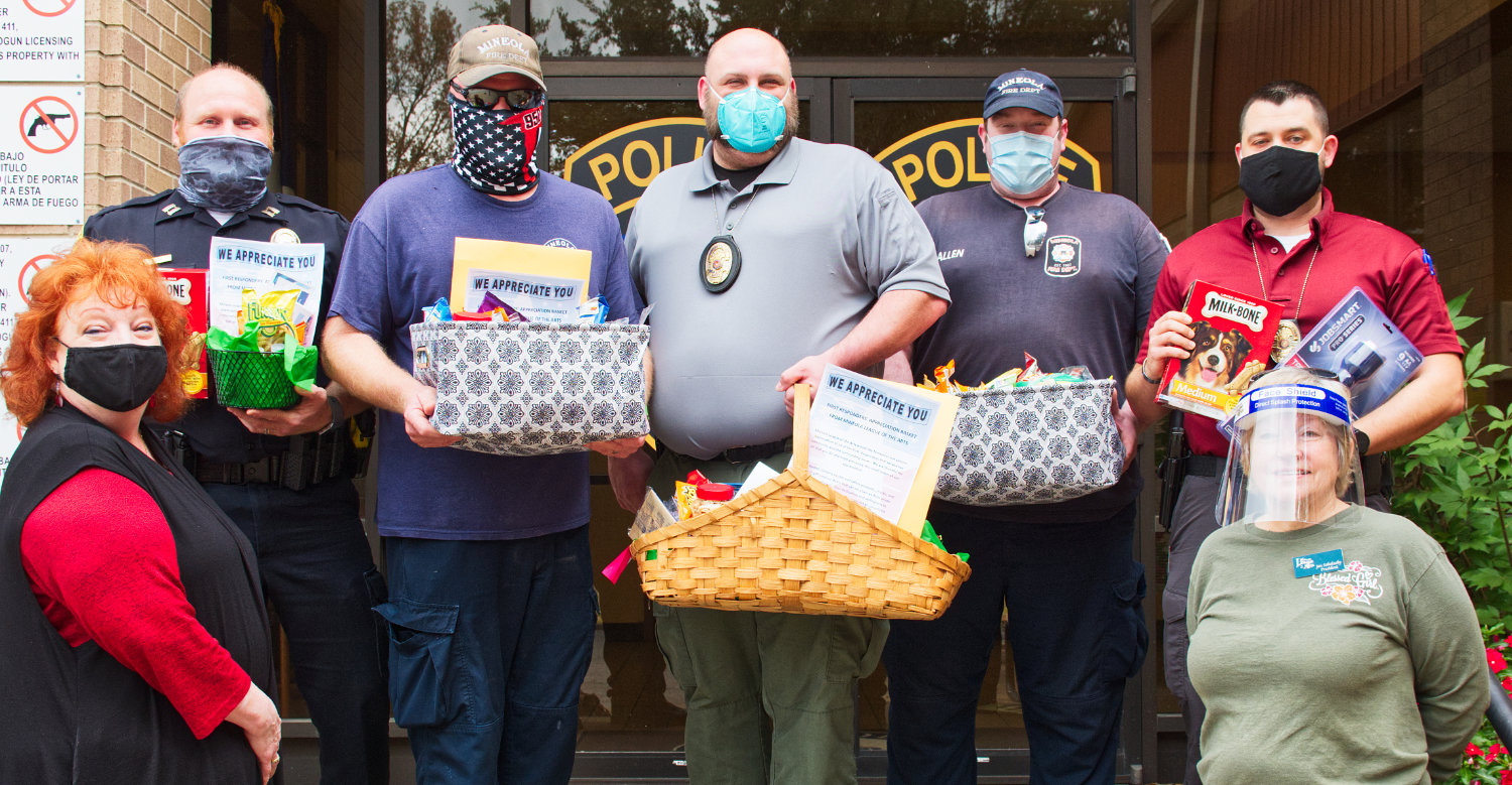 Nell French, left, and Jan Sokolosky, right, with the Mineola League of the Arts, present gift baskets to Mineola police and fire personnel last week as part of the league’s outreach to first responders around the county.